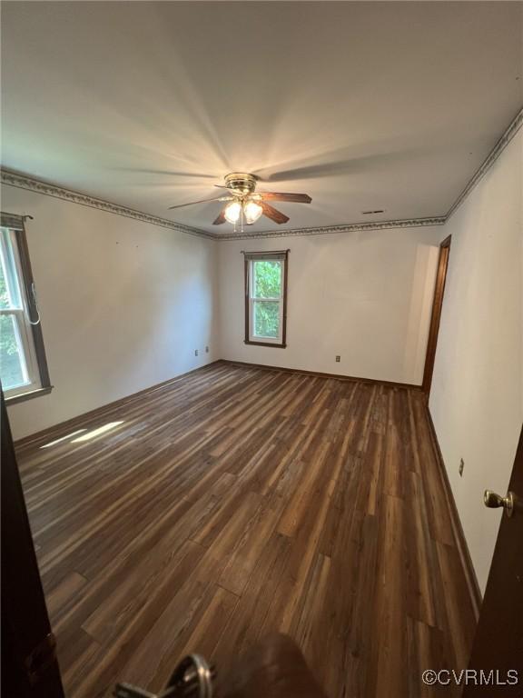 spare room featuring dark wood finished floors, a ceiling fan, and ornamental molding