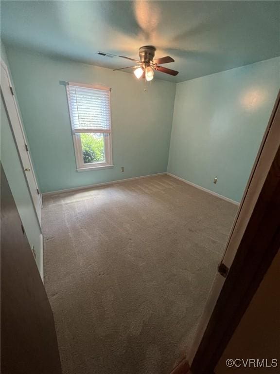 carpeted spare room featuring a ceiling fan and baseboards