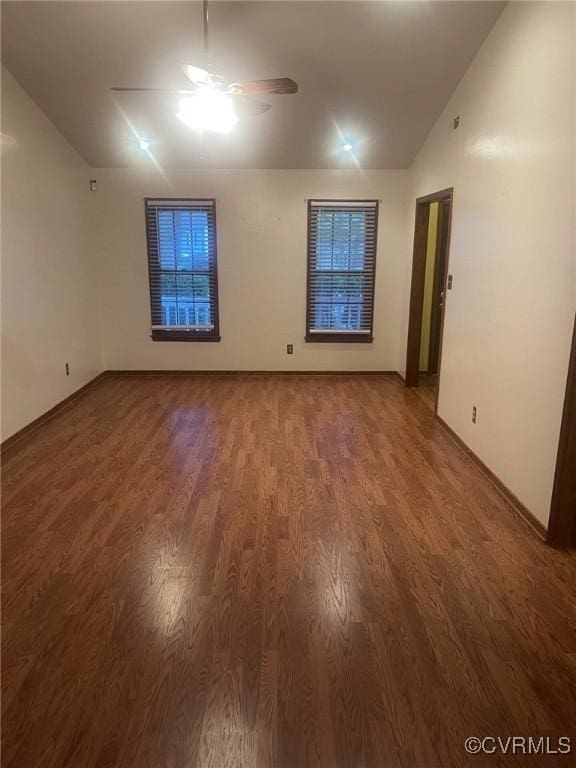 spare room featuring a ceiling fan, vaulted ceiling, wood finished floors, and baseboards