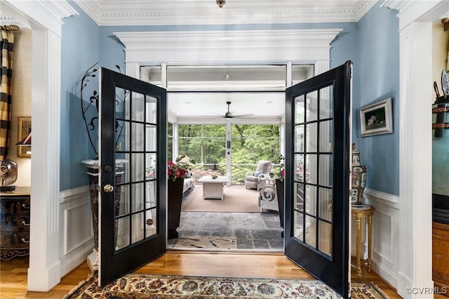 entryway featuring french doors, wood finished floors, ceiling fan, a decorative wall, and crown molding