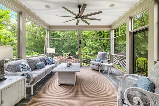 sunroom with a ceiling fan and an outdoor living space