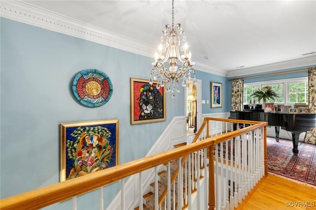 corridor featuring an upstairs landing, a chandelier, ornamental molding, and wood finished floors