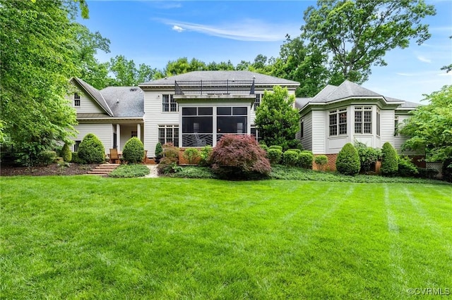 rear view of house with a yard, a shingled roof, and a sunroom