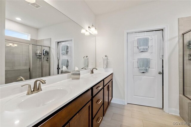 bathroom featuring a tile shower, double vanity, and baseboards