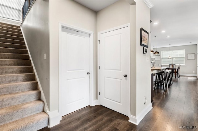 corridor featuring baseboards, dark wood-type flooring, recessed lighting, and stairs