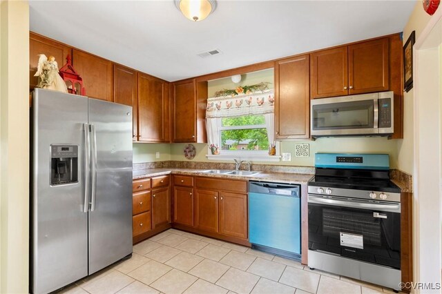 10970 Haverford Ln, North Chesterfield, VA 23236 - kitchen with stainless steel appliances, a sink, light tile patterned floors, and brown cabinets