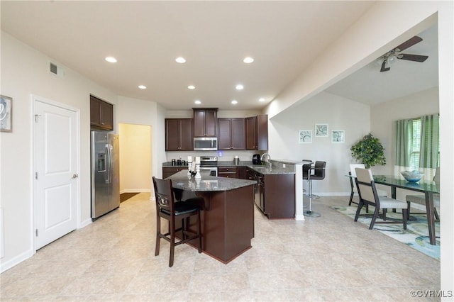 9006 Proctors Run Ct, Chesterfield, VA 23237 - kitchen with appliances with stainless steel finishes, a kitchen breakfast bar, dark brown cabinets, a kitchen island, and recessed lighting