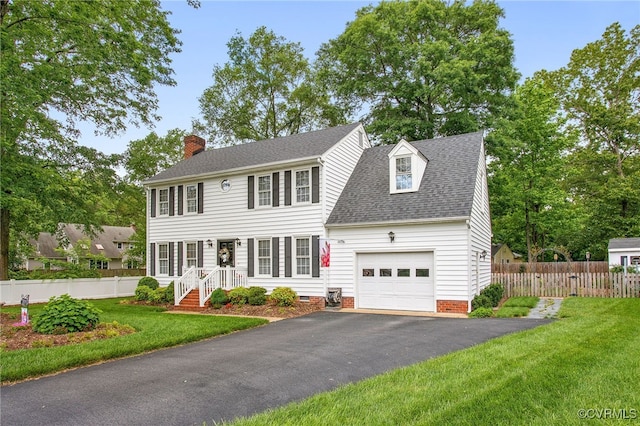 colonial home with a chimney, an attached garage, asphalt driveway, a shingled roof, and crawl space