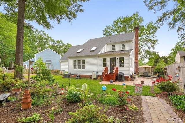 back of property featuring a chimney, a patio area, a shingled roof, and central AC
