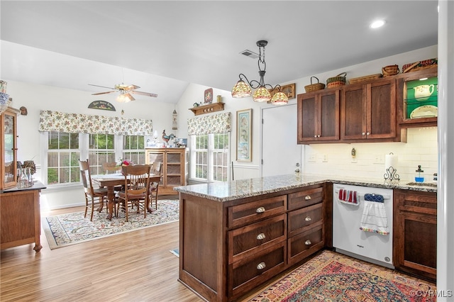kitchen with white dishwasher, a peninsula, backsplash, vaulted ceiling, and a ceiling fan
