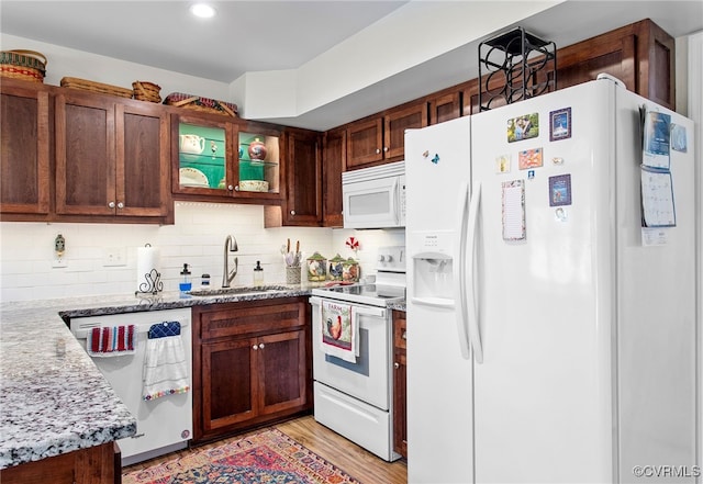 kitchen with white appliances, a sink, tasteful backsplash, light wood-style flooring, and recessed lighting