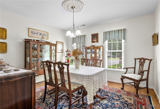 dining area with light wood-style floors, a chandelier, and baseboards