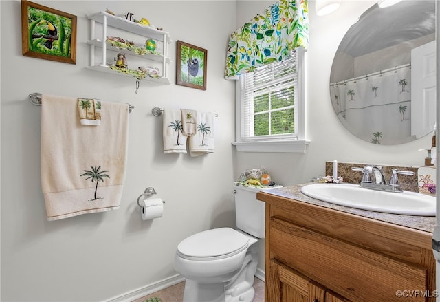 bathroom with toilet, vanity, and baseboards
