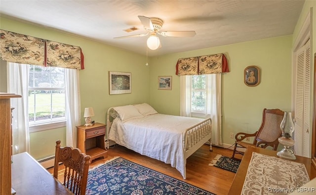 68 Family Ln, Cobbs Creek, VA 23035 - bedroom featuring multiple windows, wood finished floors, a baseboard heating unit, and a ceiling fan