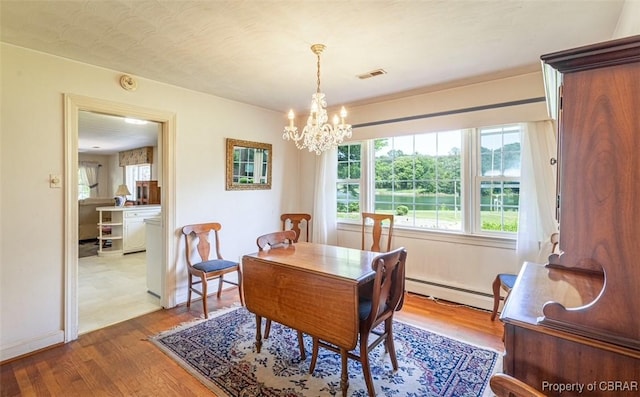 68 Family Ln, Cobbs Creek, VA 23035 - dining space featuring a baseboard heating unit, a chandelier, plenty of natural light, and wood finished floors