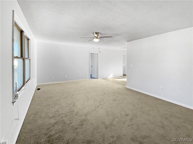carpeted empty room with a ceiling fan, a textured ceiling, and baseboards