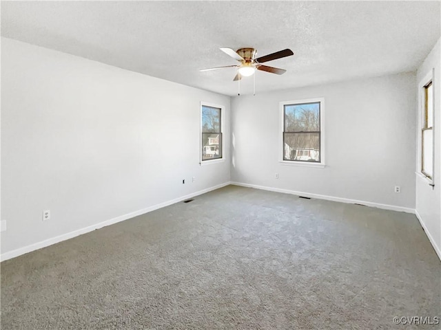 carpeted spare room featuring ceiling fan, baseboards, and a textured ceiling