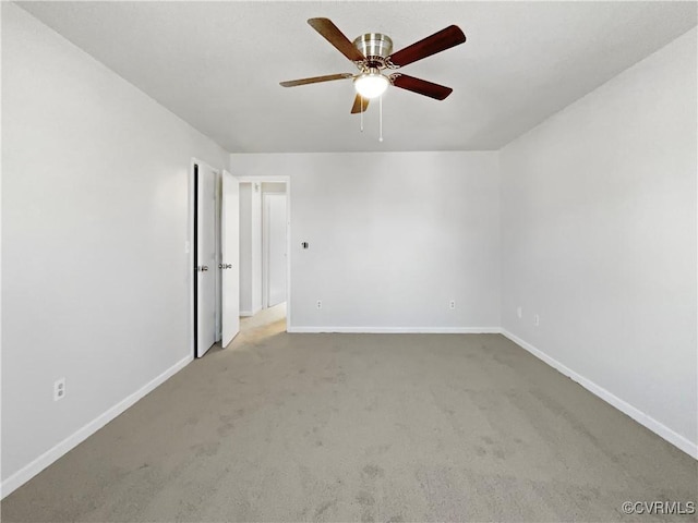 carpeted empty room with a ceiling fan and baseboards