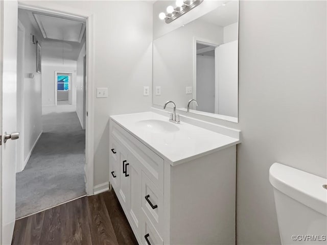 bathroom with vanity, wood finished floors, toilet, and baseboards