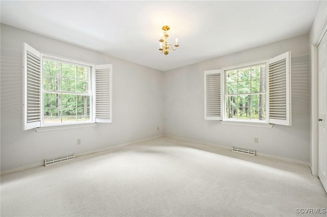 carpeted spare room with a chandelier, healthy amount of natural light, and baseboards