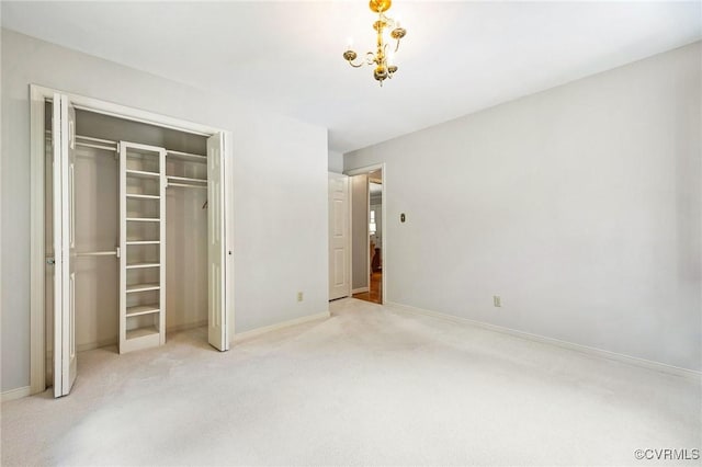 unfurnished bedroom featuring carpet floors, baseboards, a closet, and a chandelier