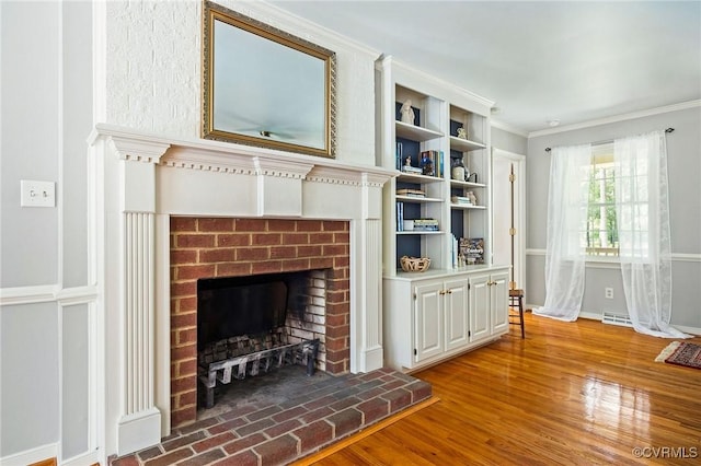 unfurnished living room with a brick fireplace, crown molding, wood finished floors, and baseboards
