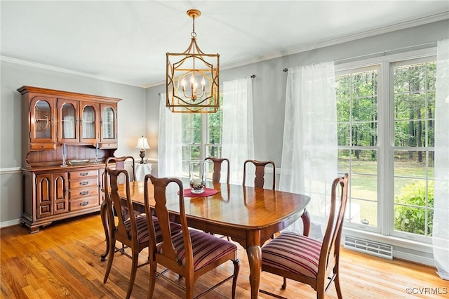 dining area featuring a chandelier, healthy amount of natural light, light wood-style floors, and ornamental molding