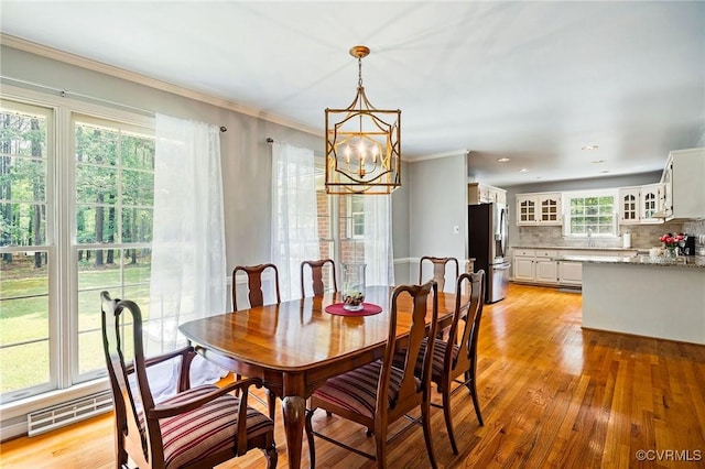 dining room featuring a chandelier, light wood-style floors, and ornamental molding