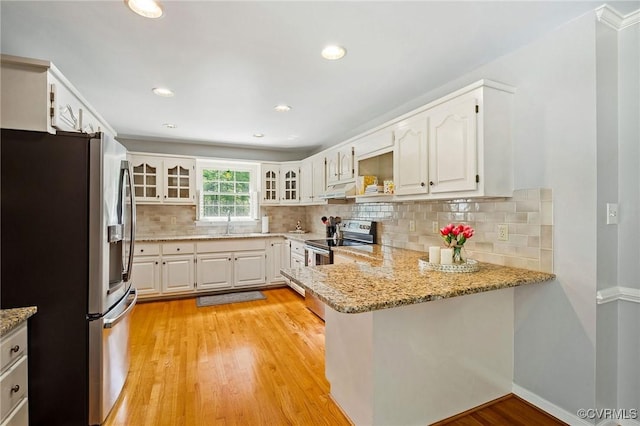 kitchen with appliances with stainless steel finishes, a peninsula, light stone countertops, white cabinetry, and recessed lighting