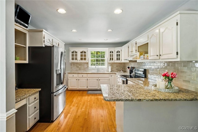 kitchen with appliances with stainless steel finishes, a sink, a peninsula, glass insert cabinets, and under cabinet range hood