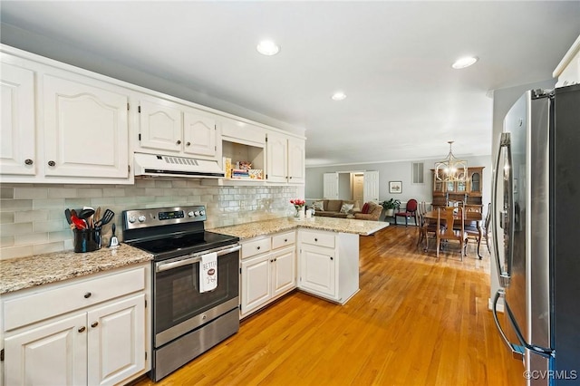 kitchen featuring appliances with stainless steel finishes, under cabinet range hood, a peninsula, white cabinets, and a chandelier