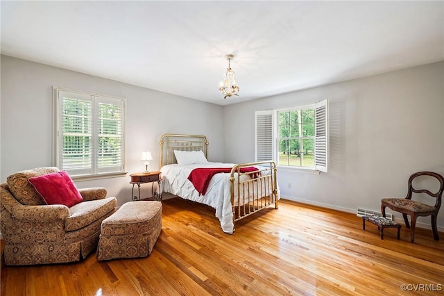 bedroom with light wood-style floors, a chandelier, and baseboards