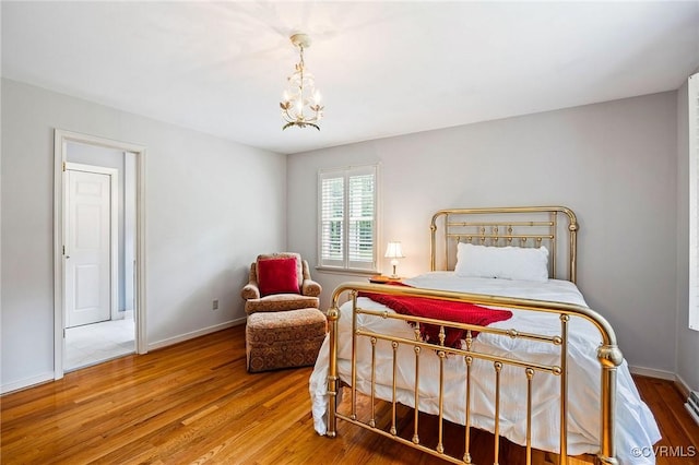 bedroom featuring wood finished floors, a chandelier, and baseboards