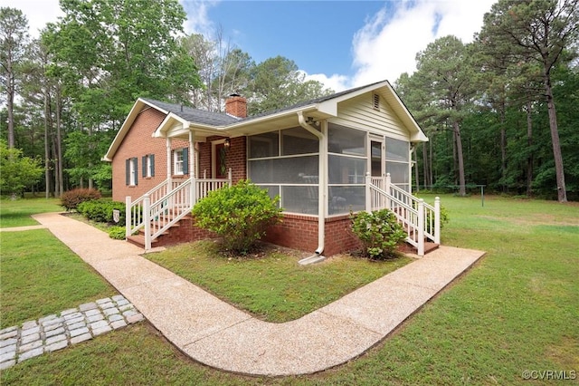 single story home with brick siding, a chimney, a front lawn, and a sunroom
