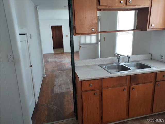 kitchen with a sink, light countertops, wood finished floors, and brown cabinetry