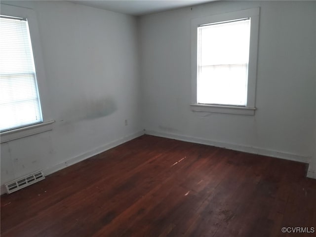 empty room featuring wood finished floors, plenty of natural light, and baseboards