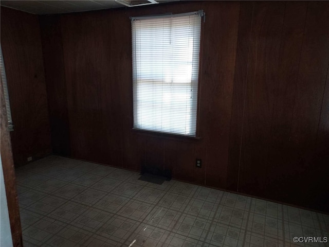 unfurnished room featuring plenty of natural light, wood walls, and light floors