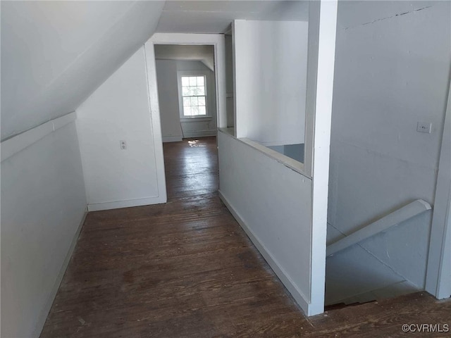 corridor featuring wood finished floors, lofted ceiling, and baseboards