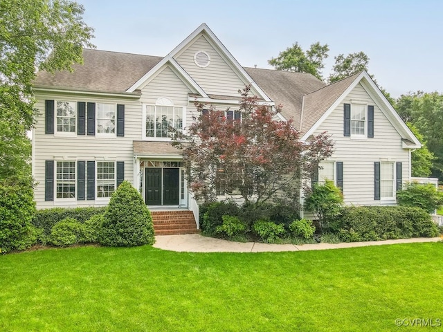 view of front of house featuring a front lawn, a shingled roof, and entry steps