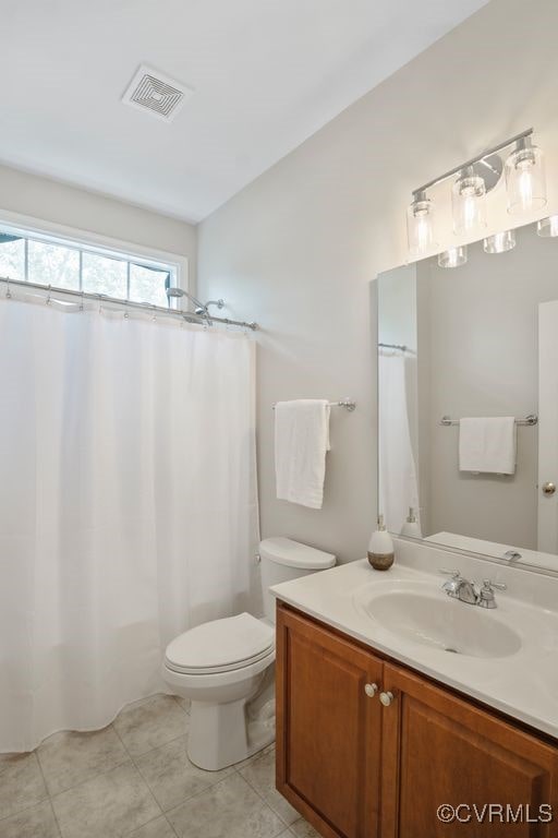 full bath featuring toilet, vanity, and tile patterned flooring