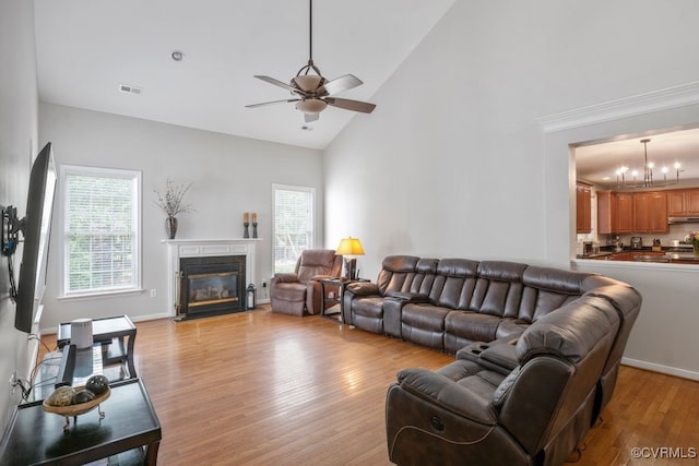 living area featuring a ceiling fan, high vaulted ceiling, light wood-style flooring, and a premium fireplace