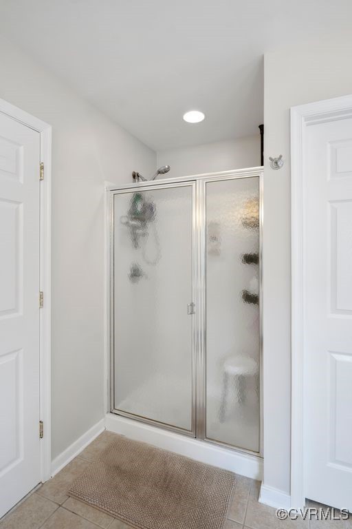 bathroom featuring tile patterned flooring, a shower stall, and baseboards