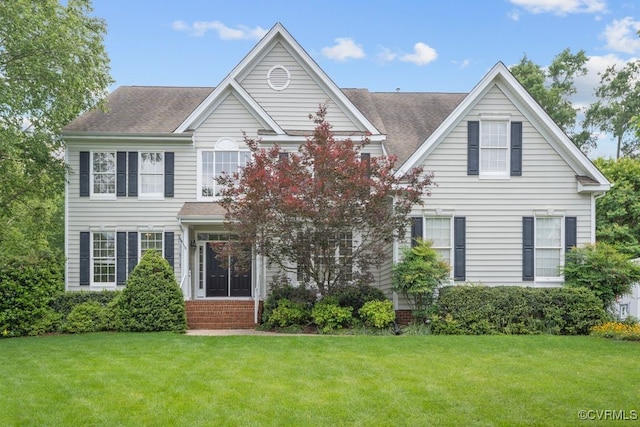 view of front facade with a front lawn and a shingled roof