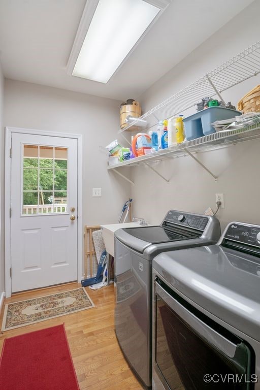 clothes washing area with washer and dryer and light wood finished floors