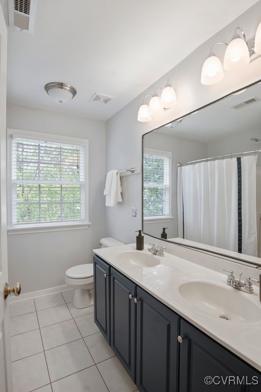 bathroom with tile patterned floors, toilet, double vanity, and baseboards