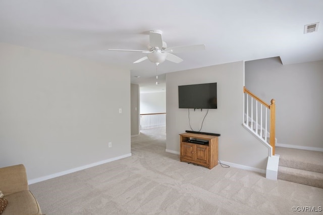 unfurnished living room featuring light carpet, a ceiling fan, baseboards, and stairway