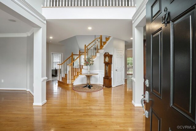entryway with light wood-style flooring, stairs, crown molding, baseboards, and recessed lighting