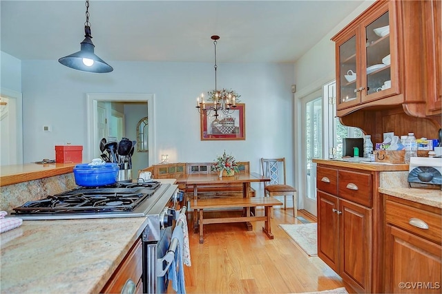 29507 Monroe Rd Unit 1, Franklin, VA 23851 - kitchen with gas range, brown cabinetry, light wood finished floors, a chandelier, and decorative light fixtures