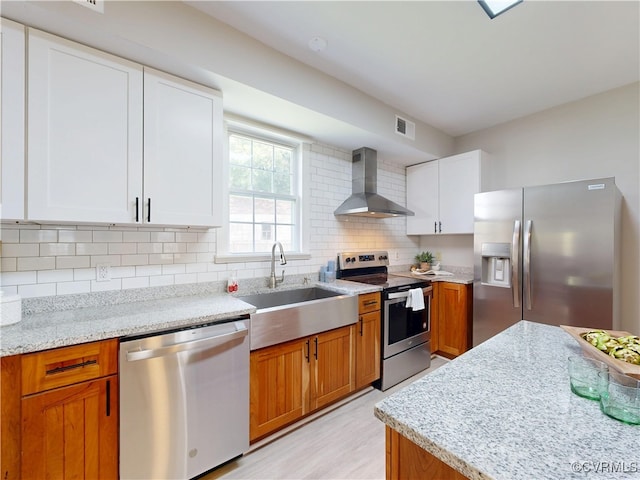56 Mancha Ave, Claremont, VA 23899 - kitchen with stainless steel appliances, wall chimney range hood, decorative backsplash, light stone countertops, and white cabinets