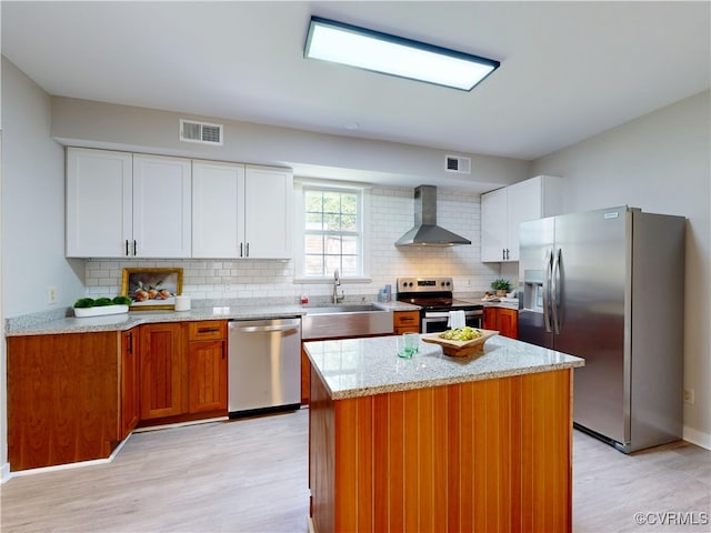 56 Mancha Ave, Claremont, VA 23899 - kitchen featuring appliances with stainless steel finishes, wall chimney range hood, a sink, light wood finished floors, and backsplash